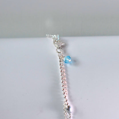 Close up of option blue crystal bead on sterling silver double strand beaded anklet with heart centre. 