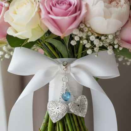 Handmade double wedding bouquet charm. Two filigree lockets are separated by blue crystal heart All the items are secured by sterling silver chain and a lobster clasp. Shown on a wedding bouquet
