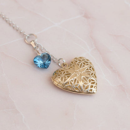 Wedding bouquet locket. A filigree locket that opens to take one photo is suspended from a sterling silver chain and next to a high quality pale blue crystal heart. The chain ends in a lobster clasp so that the charm can be fastened securely to th Bride's bouquet