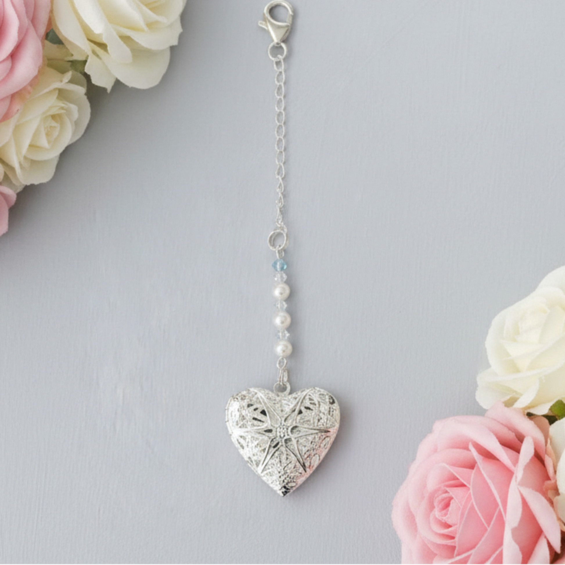 Our wedding bouquet memorial charm has a filigree opening locket which  is suspended from a row of shimmering clear crystals and glass pearts. Topped with a tiny blue crystal as a nod to something blue. Finished with a sterling silver chain and clasp, it can be securely fixed to the Bride's bouquet