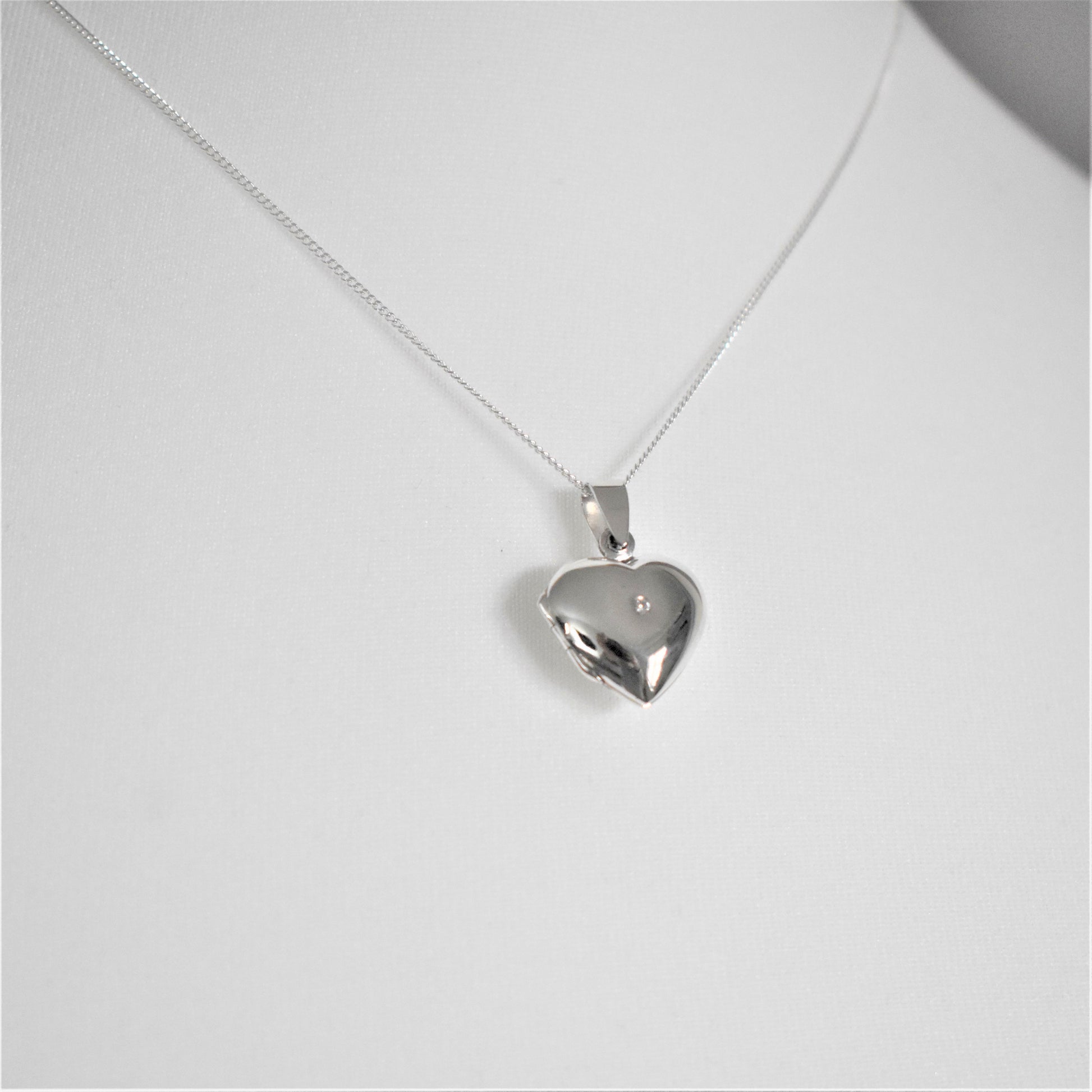 Silver heart-shaped opening locket necklace with a cubic zirconia stone in the centre