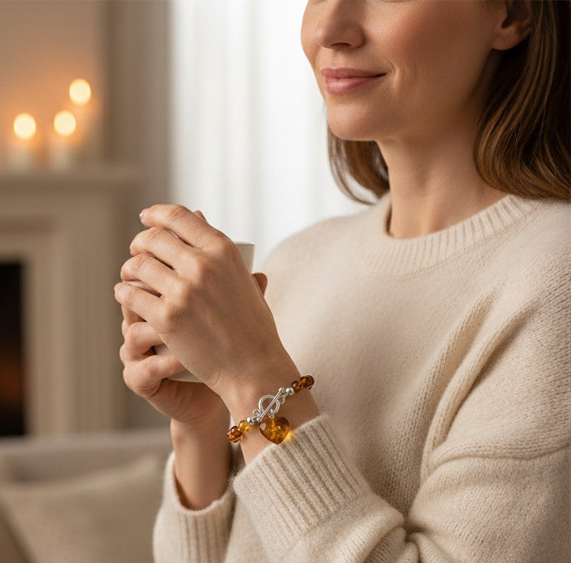 Cognac amber bracelet fastened with sterling silver TBar clasp and dangling heart charm. 