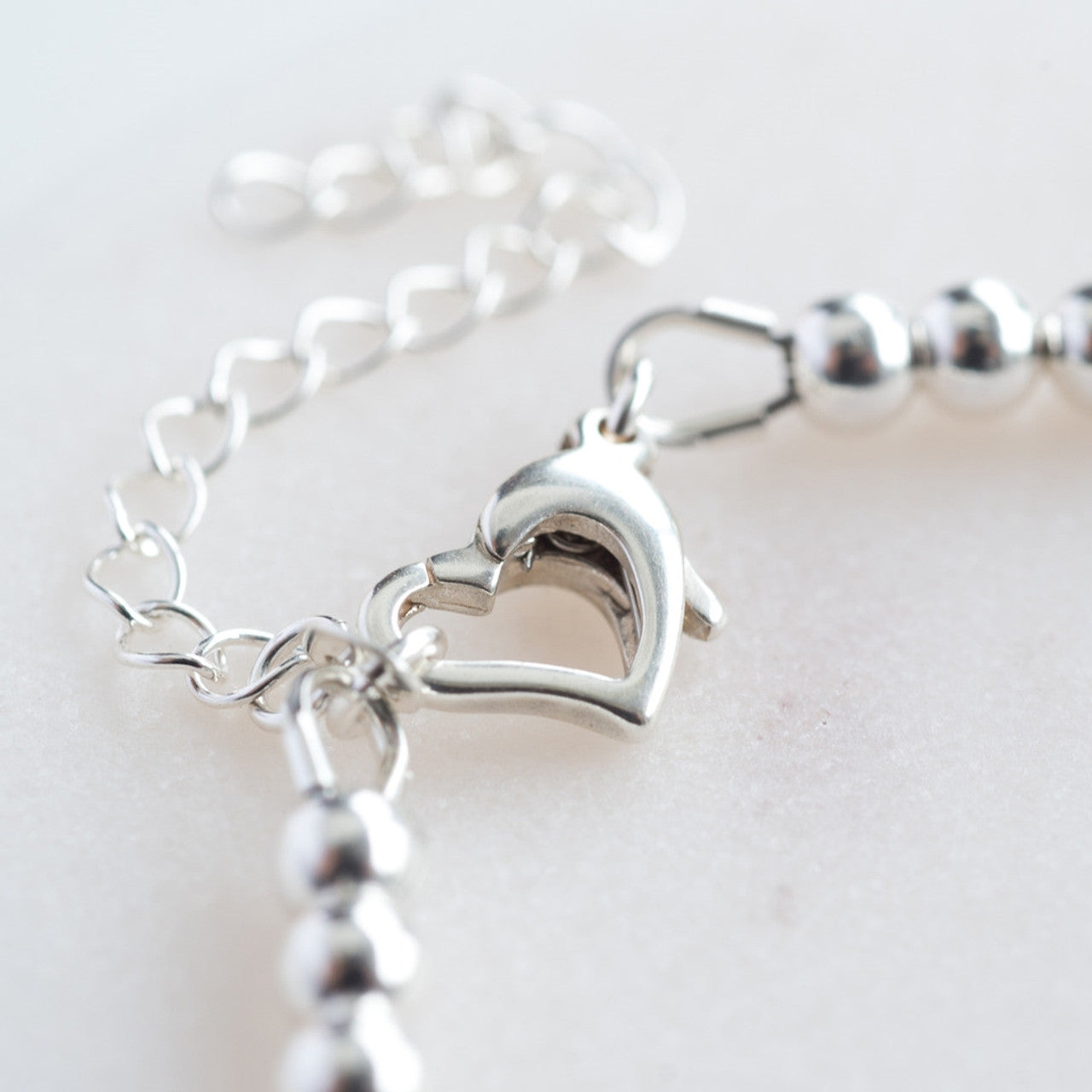 close up of heart shaped clasp on sterling silver bead and bar christening bracelet