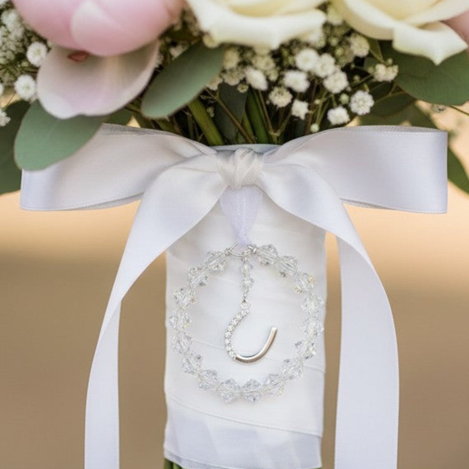 Our horseshoe boquuet charm shown on the wedding bouquet. The crystals surround a sterling silver horseshoe studded with zircona.