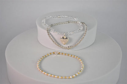 sparkling crystal locket bracelet shown with silver initial bracelet and two colour plain beaded bracelet with heart bead