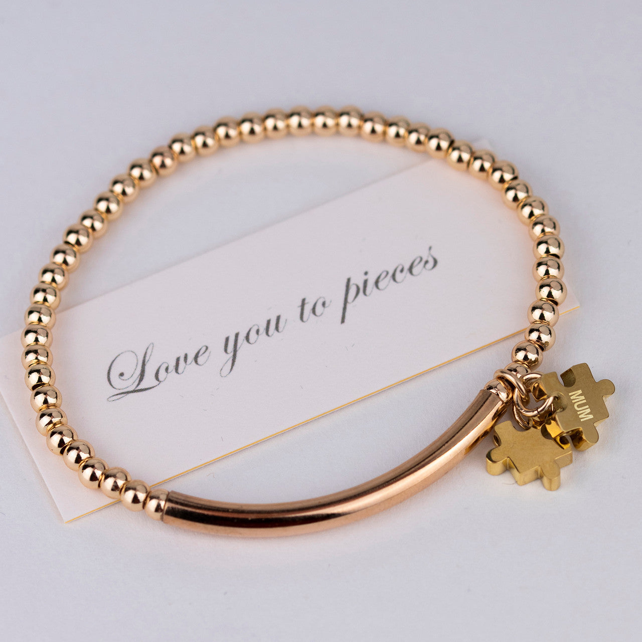 Love you to pieces bead and bar bracelet shown in gold, with one jigsaw charm engraved Mum, and accompanying love you to pieces card