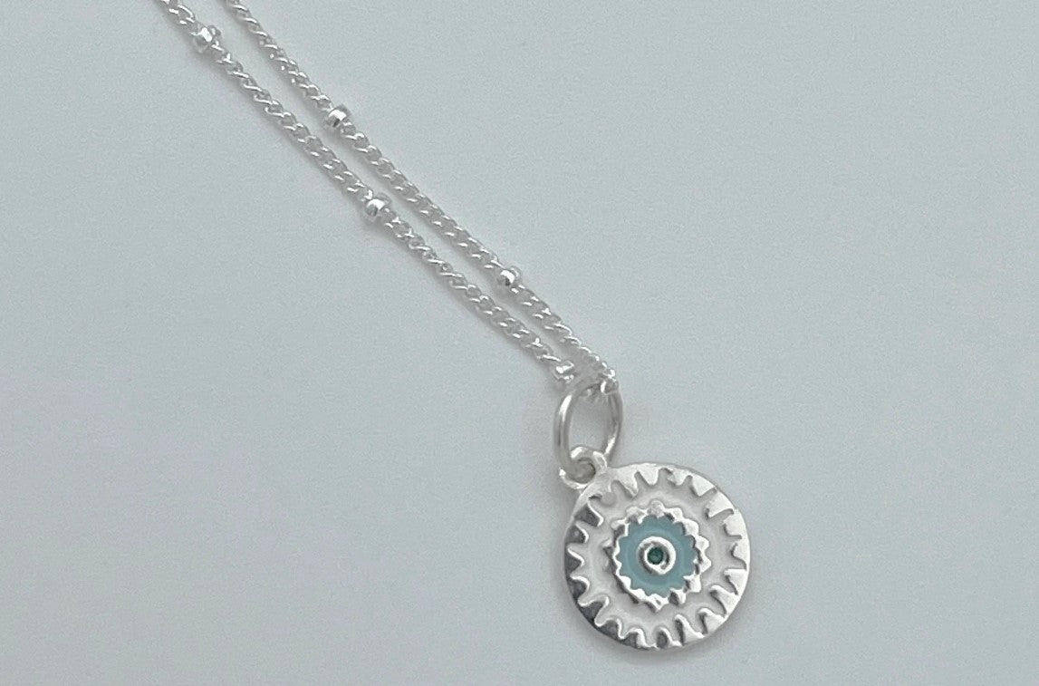 sterling silver Mandala charm with blue enamel hangs on a sparkling sterling silver satellite chain finished with a spring ring clasp.