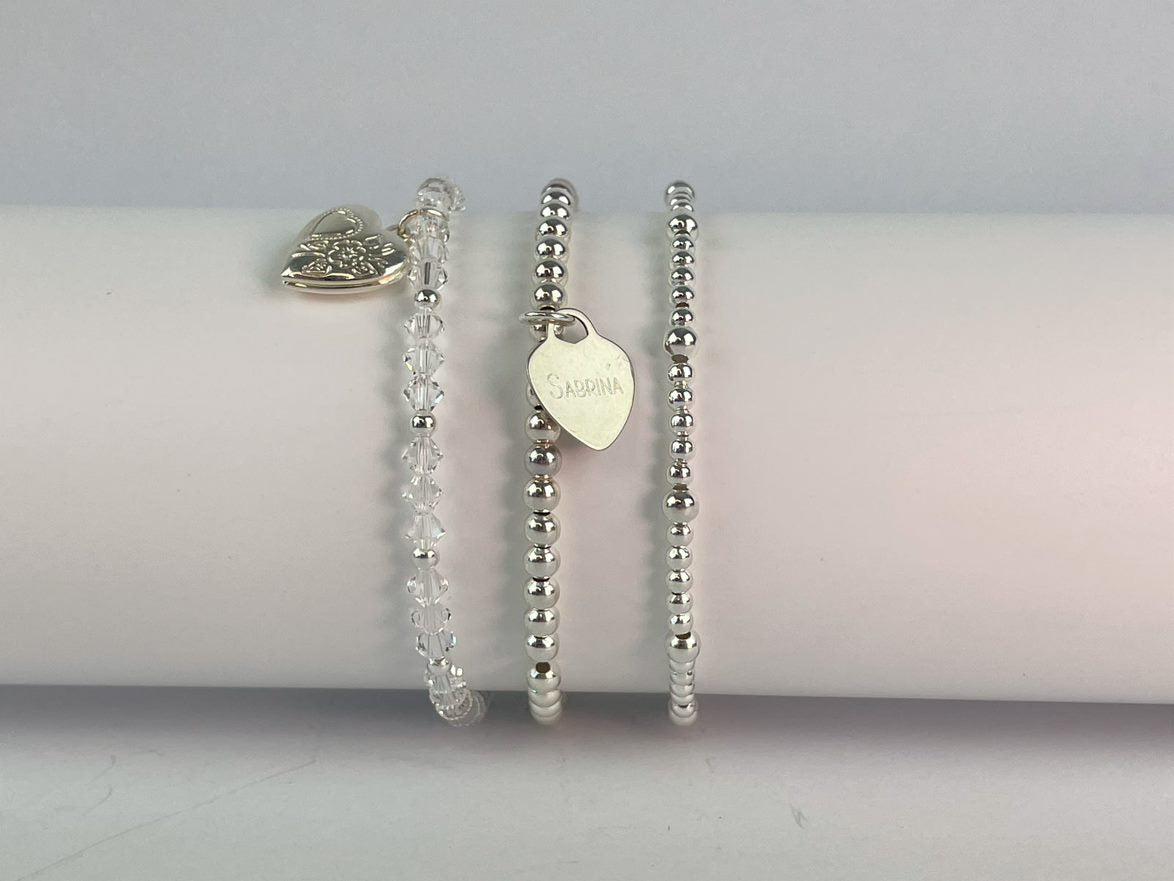 crystal locket bracelet shown with silver plated beaded bracelet carrying a sterling silver heart and a silver plated beaded bracelet