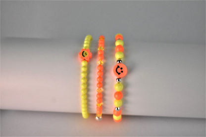 orange and yellow beaded bracelet teame with orange beads with sunshine yellow crystal bracelet and yellow neon bracelet with smiley flower face to make a perfect bracelet stack