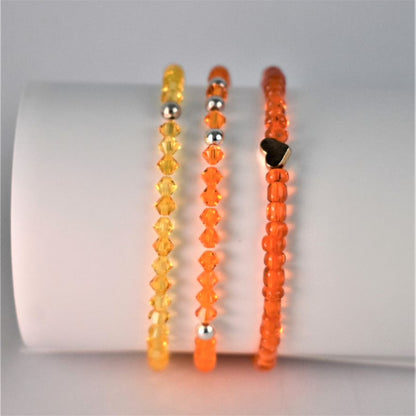 sunshine yellow crystal bracelet is shown with fiery orange beaded bracelet and orange crystal bracelet to form a bracelet stack