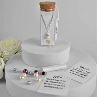 Double pearl drop pendant on silver chain is contained within a glass bottle with a scroll bridesmaid request. Bottle is finished with label  showing bridesmaid's name