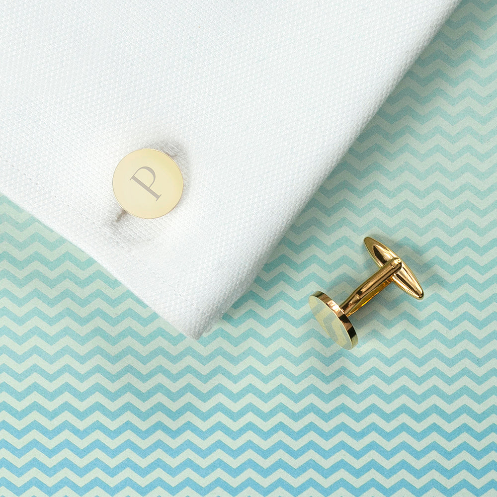 Circular gold plated cufflink shown on cuff and with single initial
