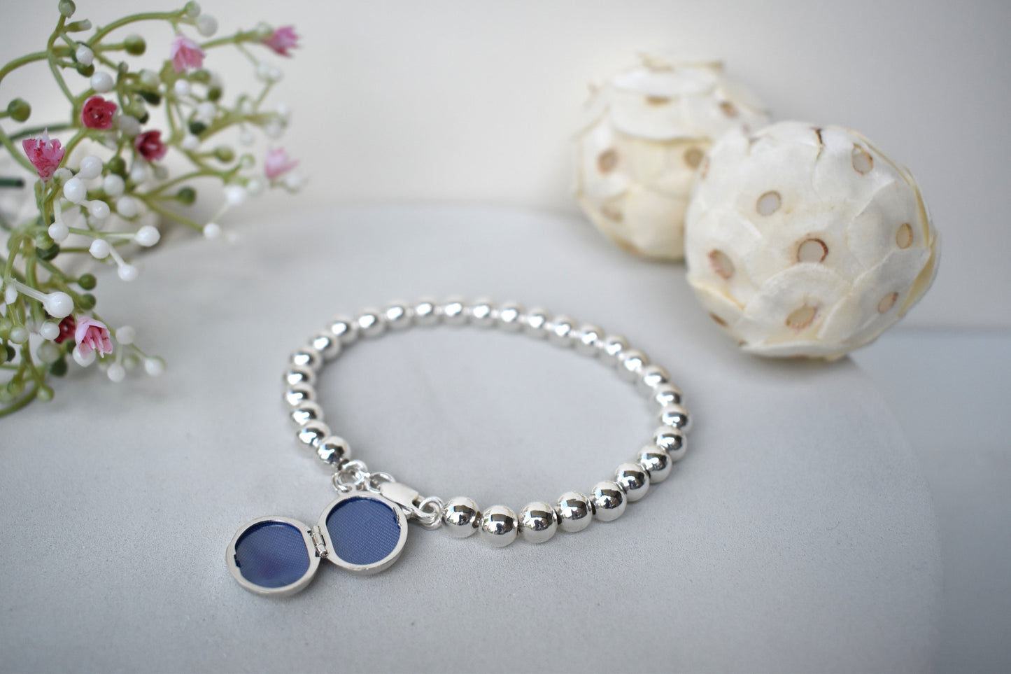 Sterling silver beaded bracelet with a lobster clasp. Next to the clasp is an oval locket that can be engraved with the wording of your choice