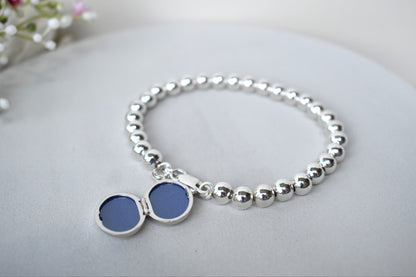 Sterling silver beaded bracelet with a lobster clasp. Next to the clasp is an oval locket that can be engraved with the wording of your choice