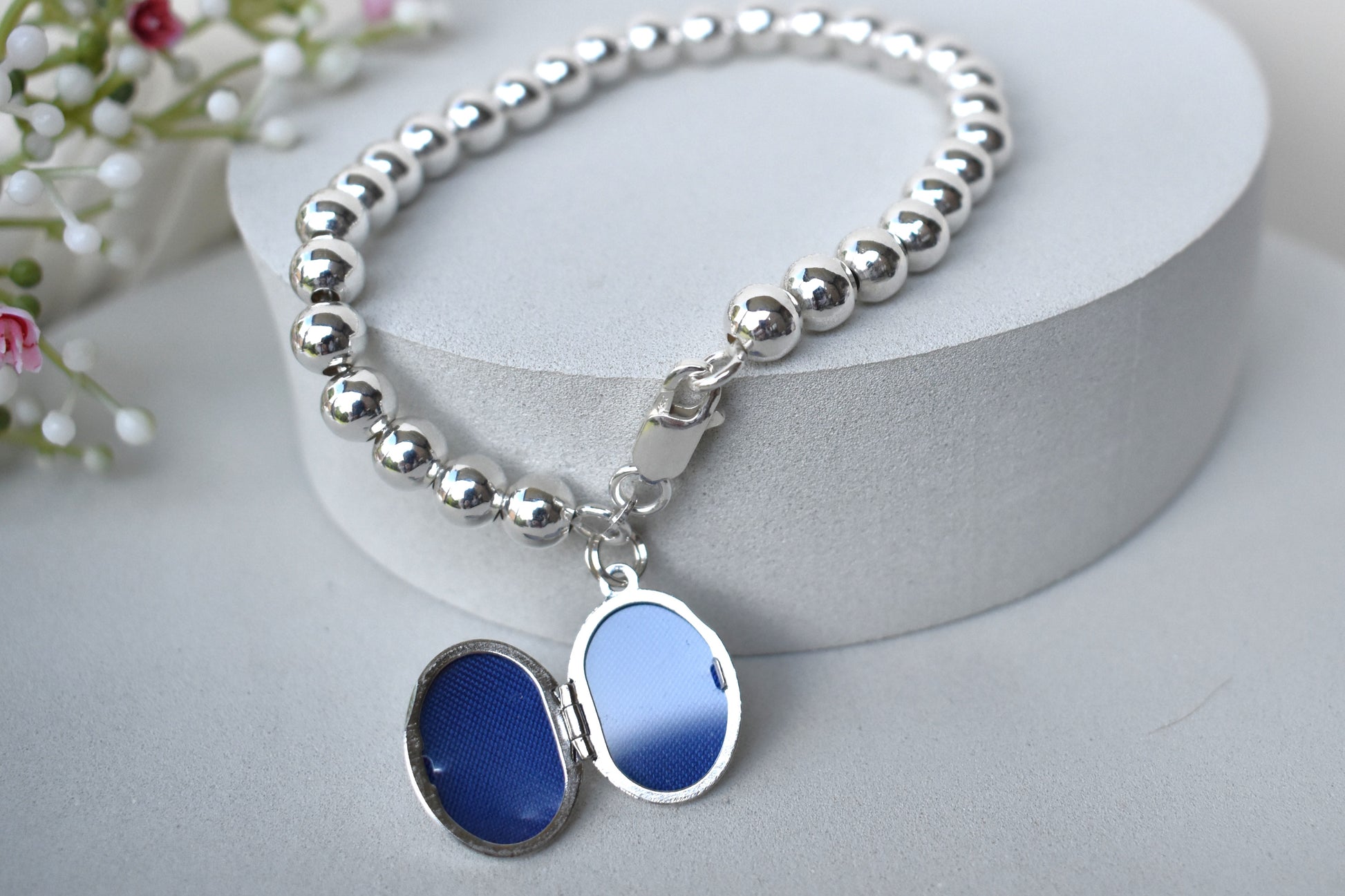 Sterling silver beaded bracelet with a lobster clasp. Next to the clasp is an oval locket that can be engraved with the wording of your choice