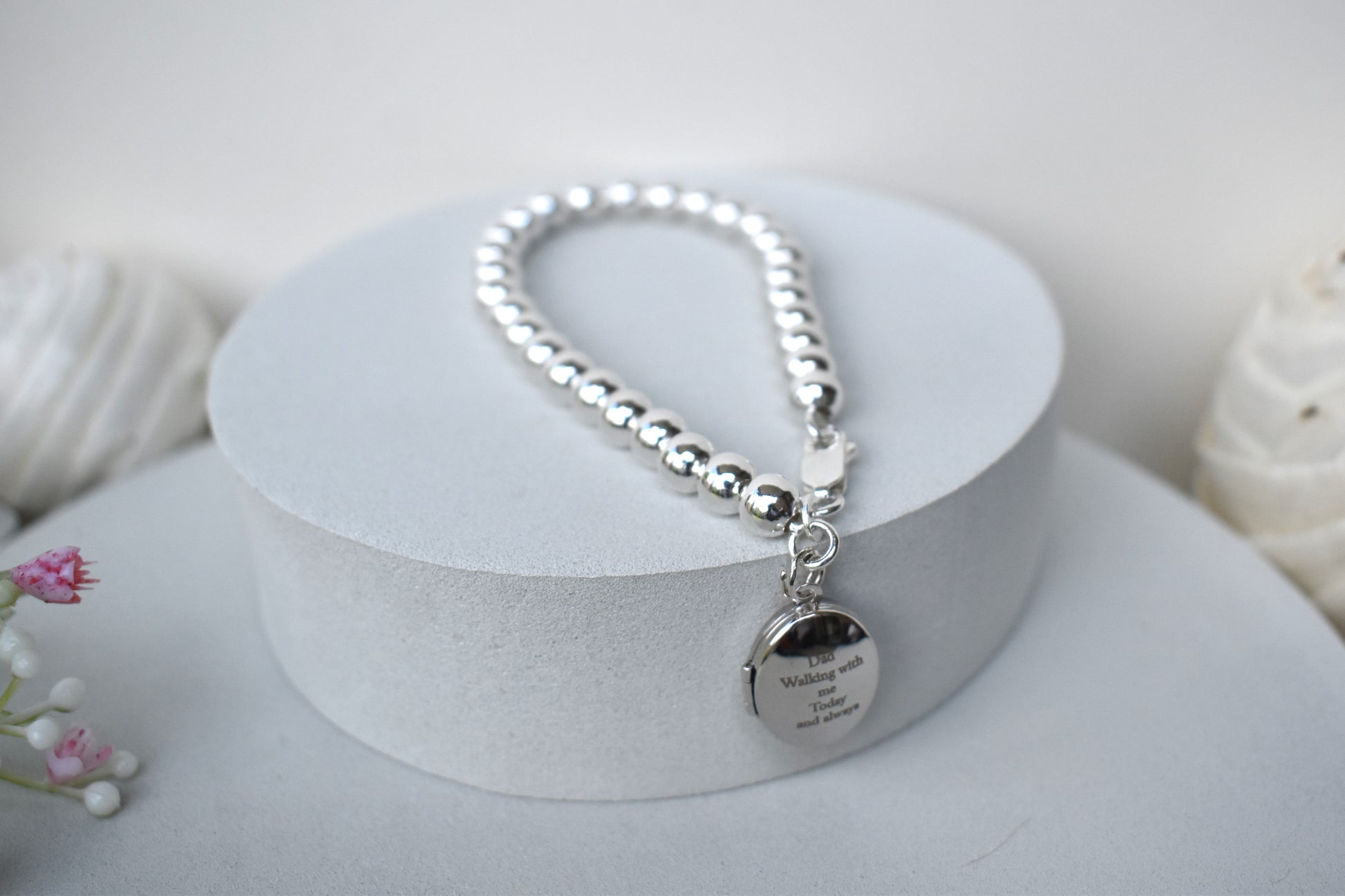 Sterling silver beaded bracelet with a lobster clasp. Next to the clasp is an oval locket that can be engraved with the wording of your choice