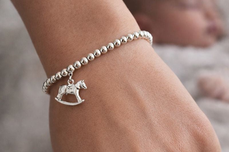 Model wears  sterling silver bracelet consisting of 4mm sterling silver beads threaded onto strong elastic and with a sterling silver rocking horse charm.