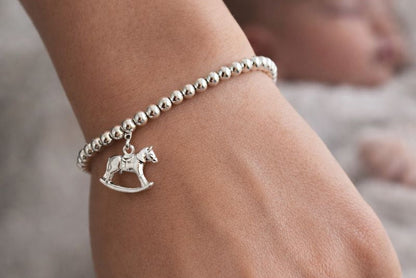 Model wears  sterling silver bracelet consisting of 4mm sterling silver beads threaded onto strong elastic and with a sterling silver rocking horse charm.