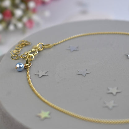 Close up of gold plated sterling silver curb anklet showing tiny blue glass pearl