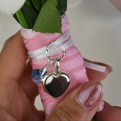 sterling silver heart shaped locket for two photos, accompanied by a blue crystal heart and threaded through a sterling silver loop. Ribbon supplied for you to attach to your bouquet. Easily detach the locket later to wear with a chain.