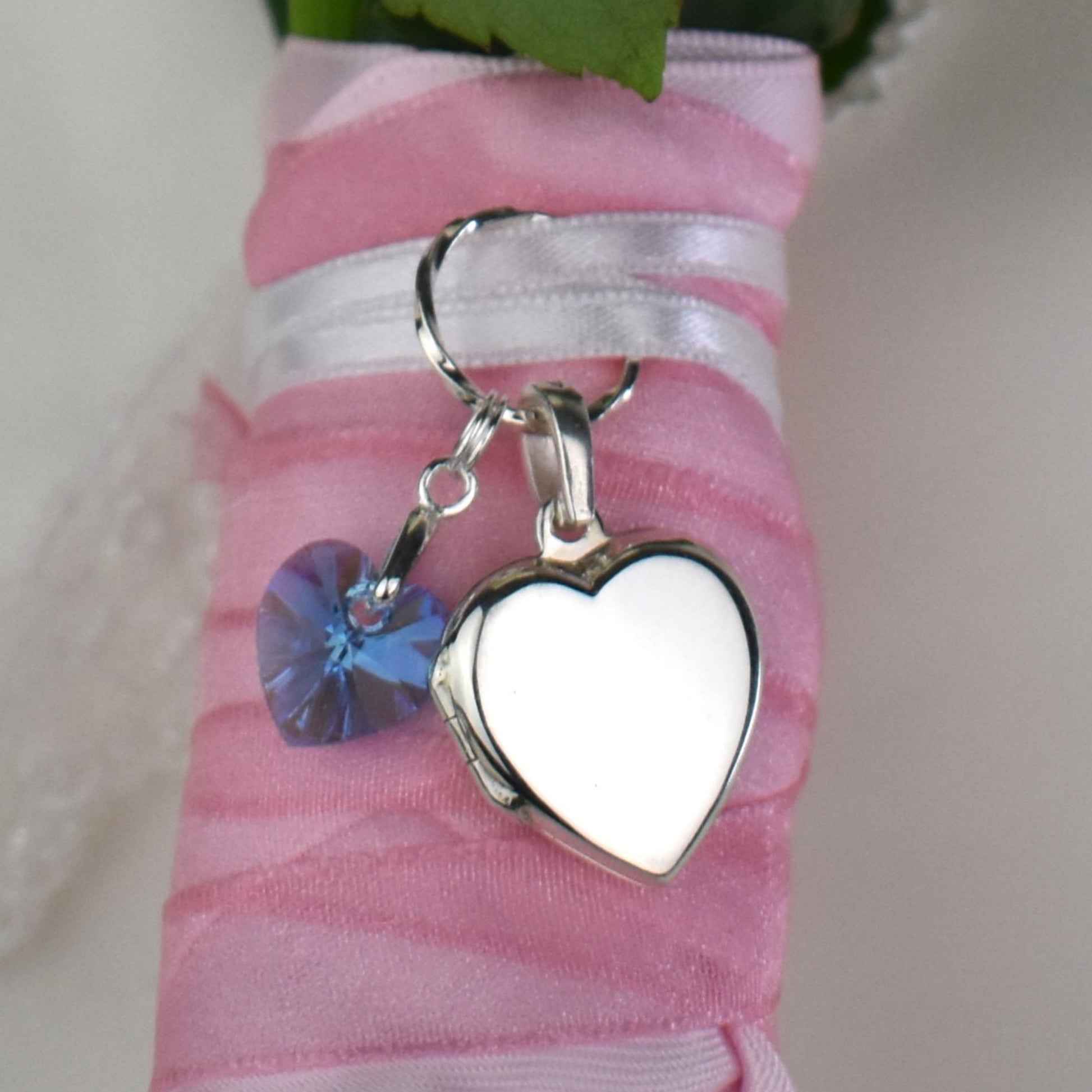 Heart shaped sterling silver locket wtih something blue crystal heart. Shown on bouquet.. Opening bail on locket means it can be detached from the ring and place on a necklace chain after the wedding.