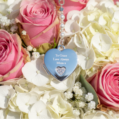 A sterling silver heart shaped locket wedding bouquet charm, engraved with wording of your choice on the front of the heart. The locket opens to add two photos of your choice. Suspended from a string of crystals and glass pearls with a tiny blue bead for your something blue.