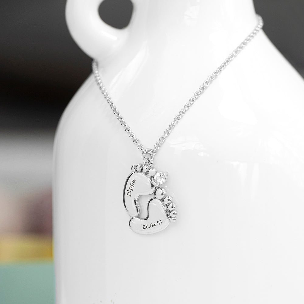 Silver plated necklace showing two baby feet, one engraved with the babys name and the other with their birth date