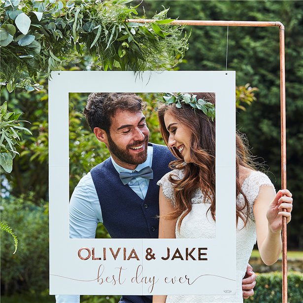 bride and groom behind customisable photo booth frame