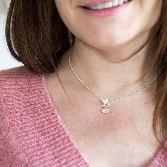 Sterling silver necklace with a tiny silver bird on a brance. Below her is a rose gold chick with an initial.