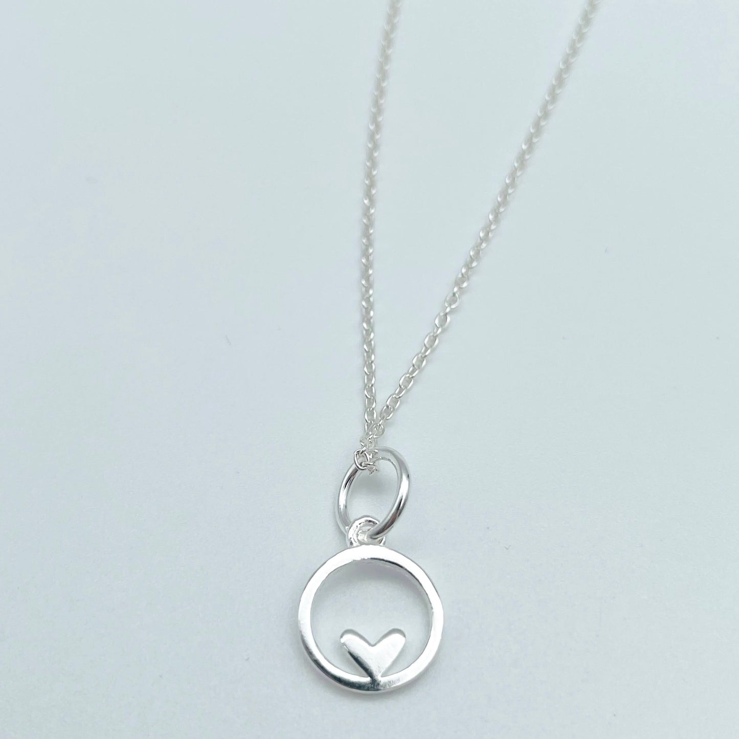 Sterling silver pendant circle with small heart motif at the bottom of the circle. 