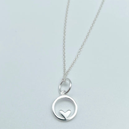 Sterling silver pendant circle with small heart motif at the bottom of the circle. 