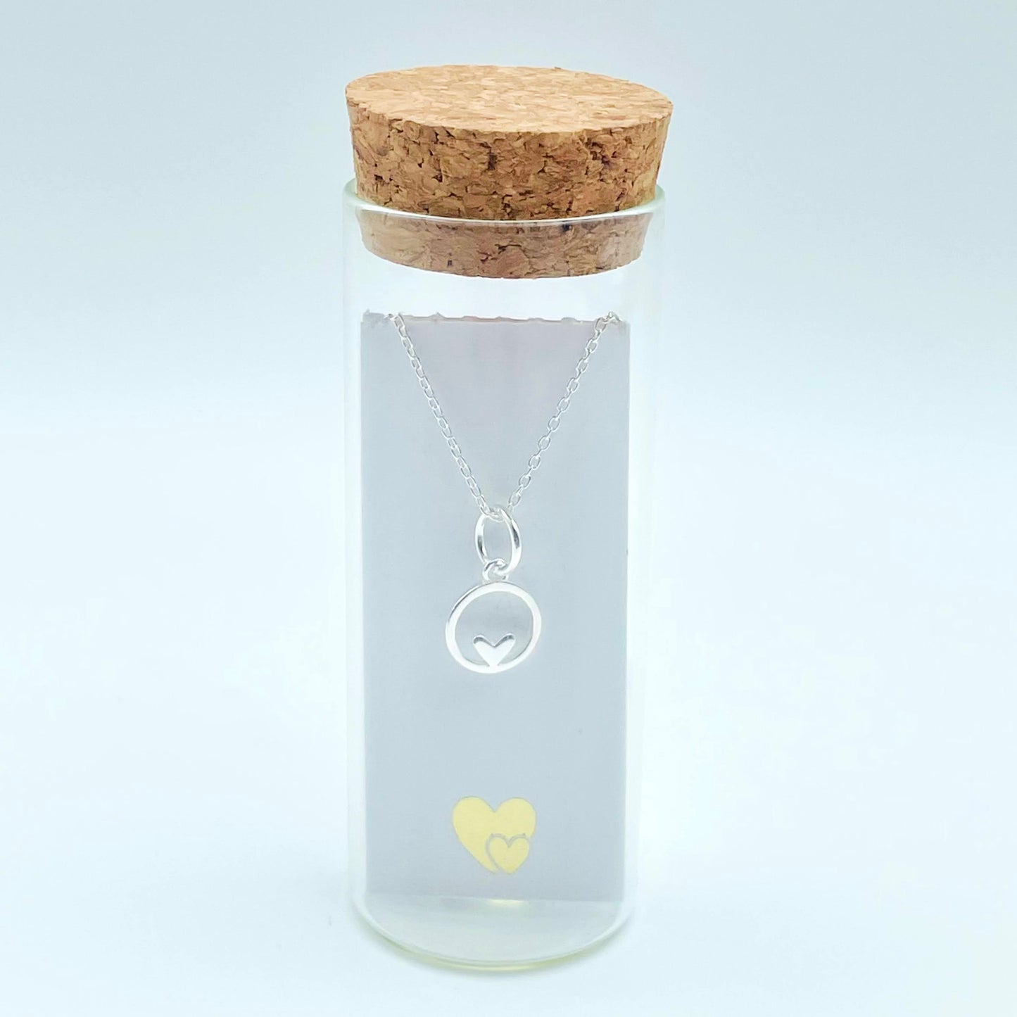 A small sterling silver circle encases a tiny sterling silver heart and is hung from a sterling silver chain. The necklace is placed in a glass bottle which also includes a scroll with a message in your wording. Part of our Message in a Bottle range. Your  pendant includes a luxury gift pouch and eco-friendly packaging