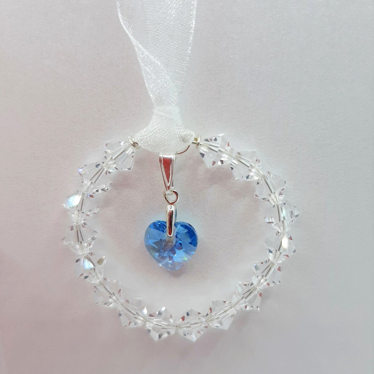 Ring of clear crystal circles surround a blue crystal heart, wedding bouquet charm