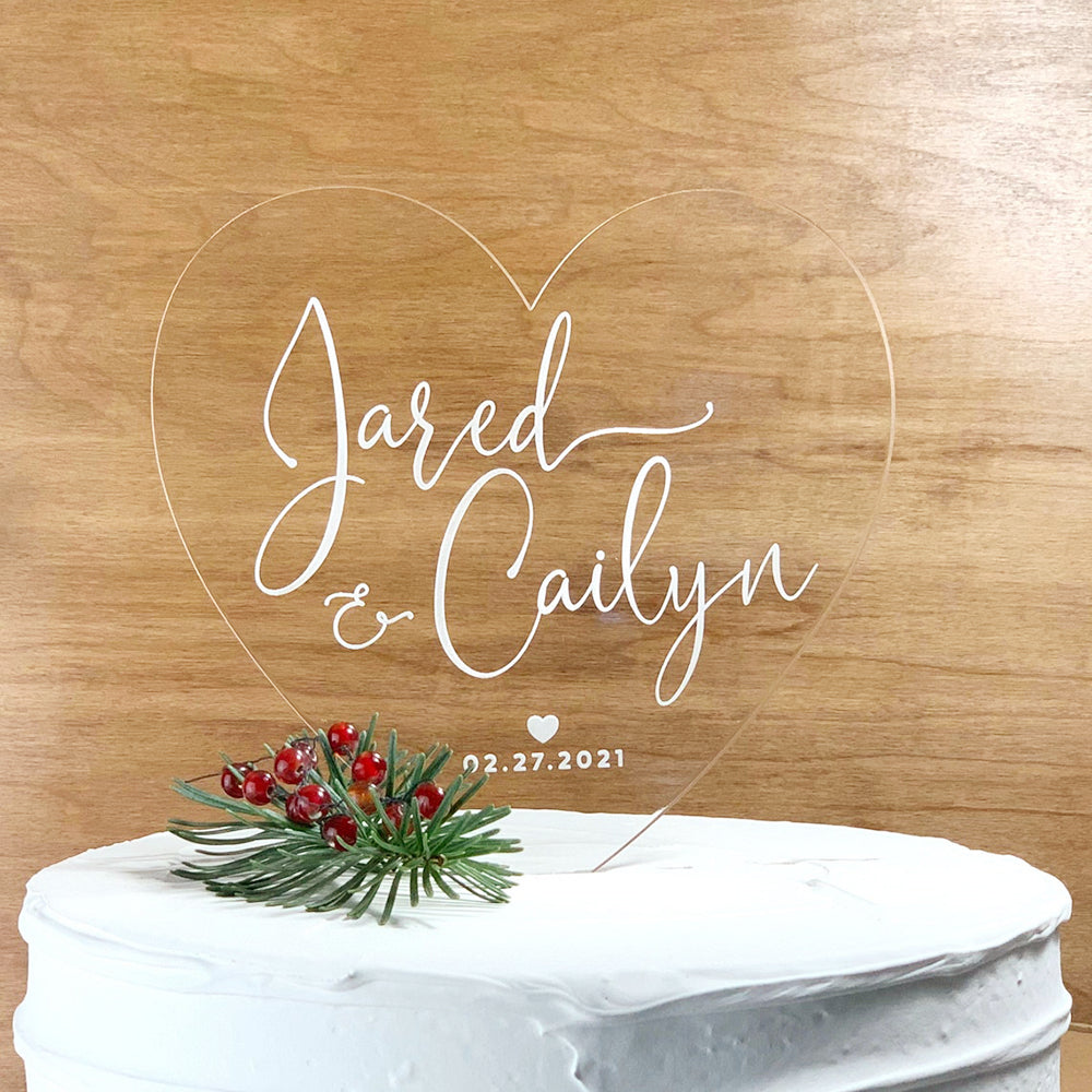 Heart shaaped acrylic cake topper with couples names and wedding date in white script