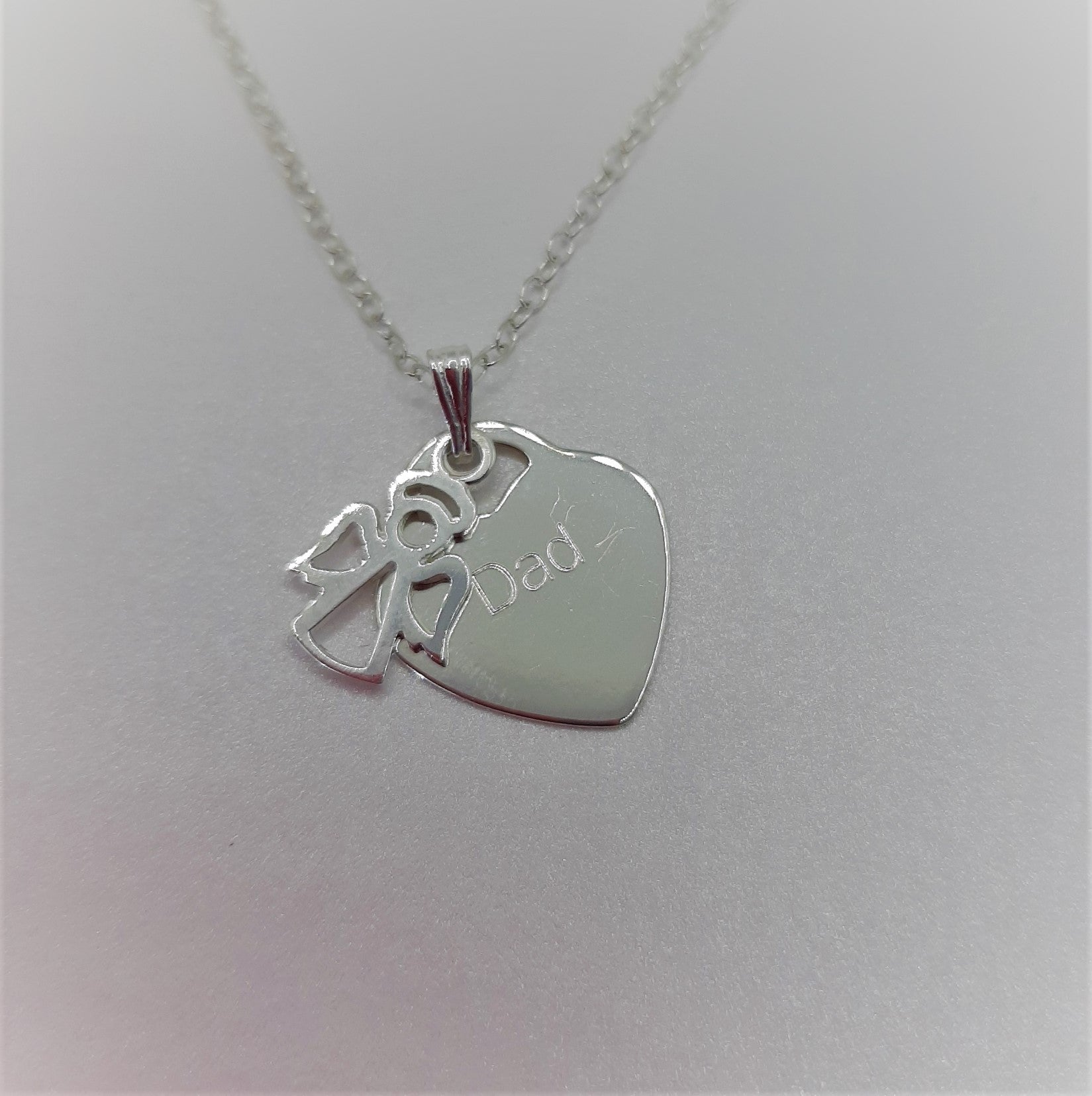 Sterling silver angel charm hung on a pendant with a sterling silver heart. Heart can be engraved with the name of your choice.