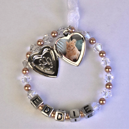 pet memorial keepsake with locket. crystals and pearls surround your pet's name. In the centre of the circle is a silver colour locket with a paw print on the front. The locket opens for you to add a photo of your beloved pet.