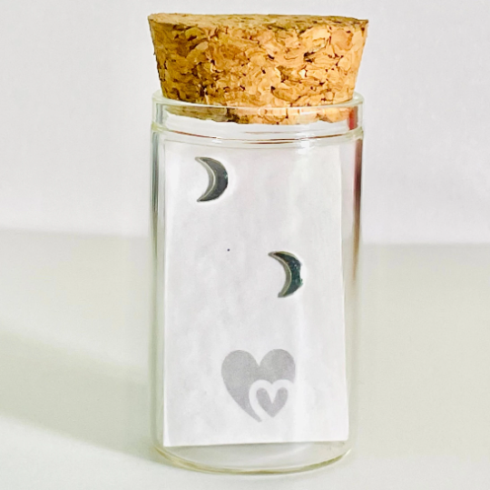 sterling silver crescent moon studs in a glass bottle with cork lid. Bottle also includes a parchment scroll for you to write your own message. 