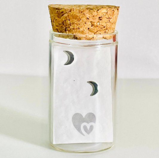 sterling silver crescent moon studs in a glass bottle with cork lid. Bottle also includes a parchment scroll for you to write your own message. 
