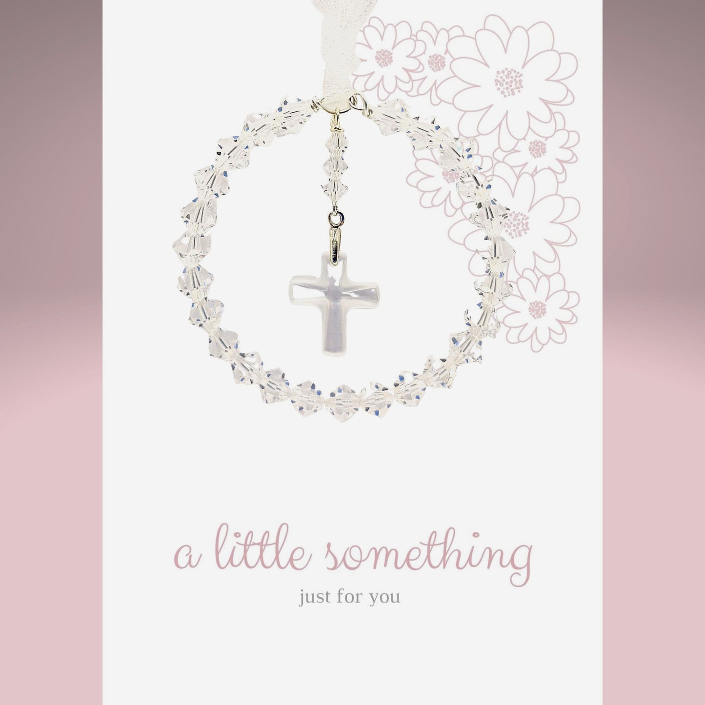 A circle of high grade austrian crystals surrounds a crystal cross suspended from the centre of the circle. Sparkling crystal ribbon completes the charm. Shown on a pre-printed card with the message "a little something just for you"