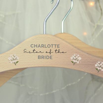 close up of centre of personalised wooden wedding hanger with three lines of text and flowers along the arms of the hanger