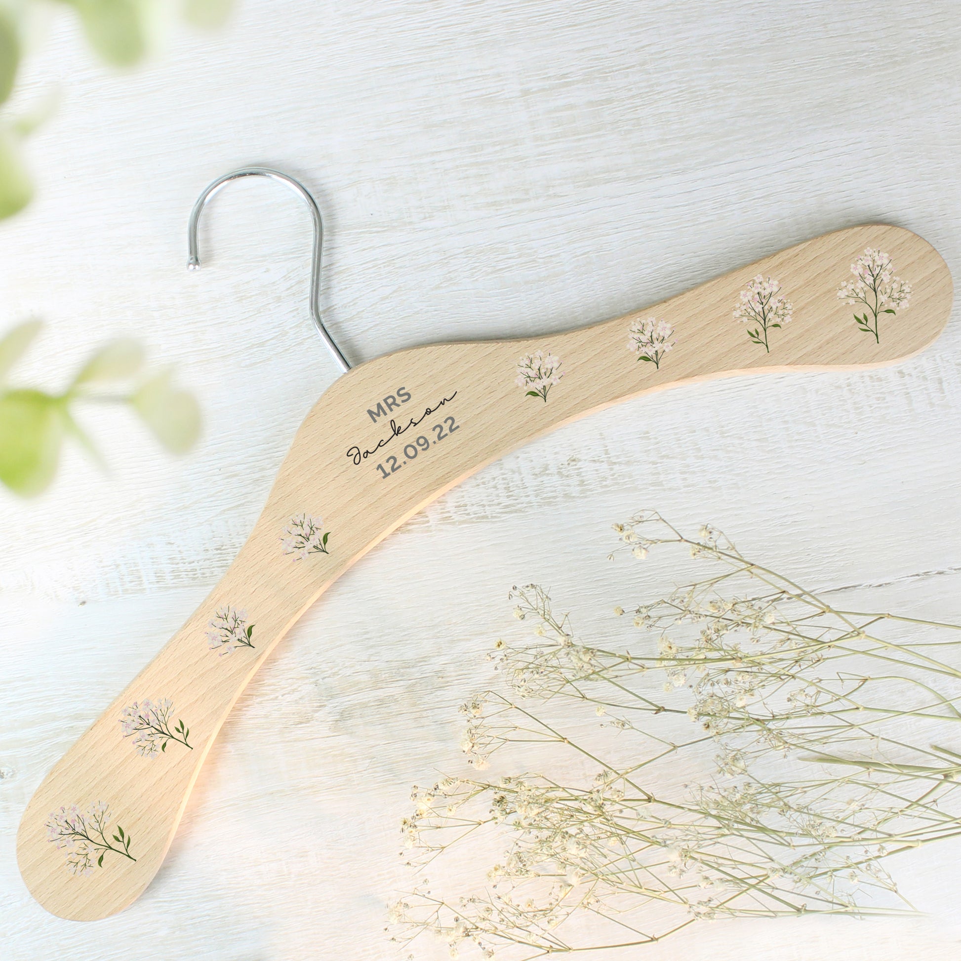 PERSONALISED wooden wedding hanger with three lines of text and flowers along the arms of the hanger
