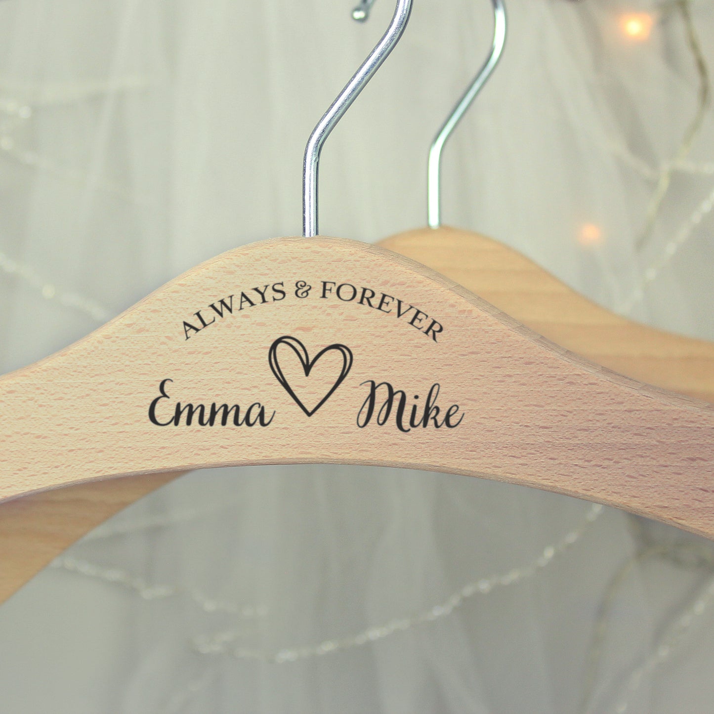 centre of personalised wooden wedding hanger with Bride & Groom's names under the words "Always and Forever" and with a pretty sketched heart between the names. Room for further personalisation on each arm of the hanger.