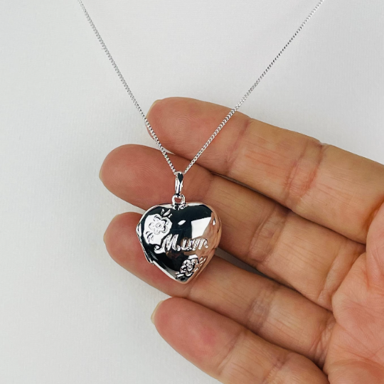 Closer view of Sterling silver heart shaped locket engraved with the word "Mum" in script and flower decoration. Suspended from a sterling silver chain.