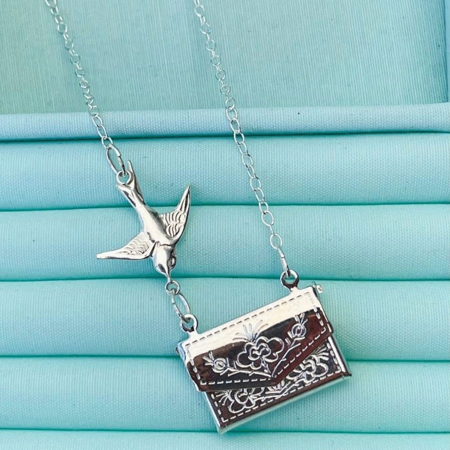 Sterling silver swallow flies towards a silver plated locket that opens to reveal the message of your choice. Secret message pendant.