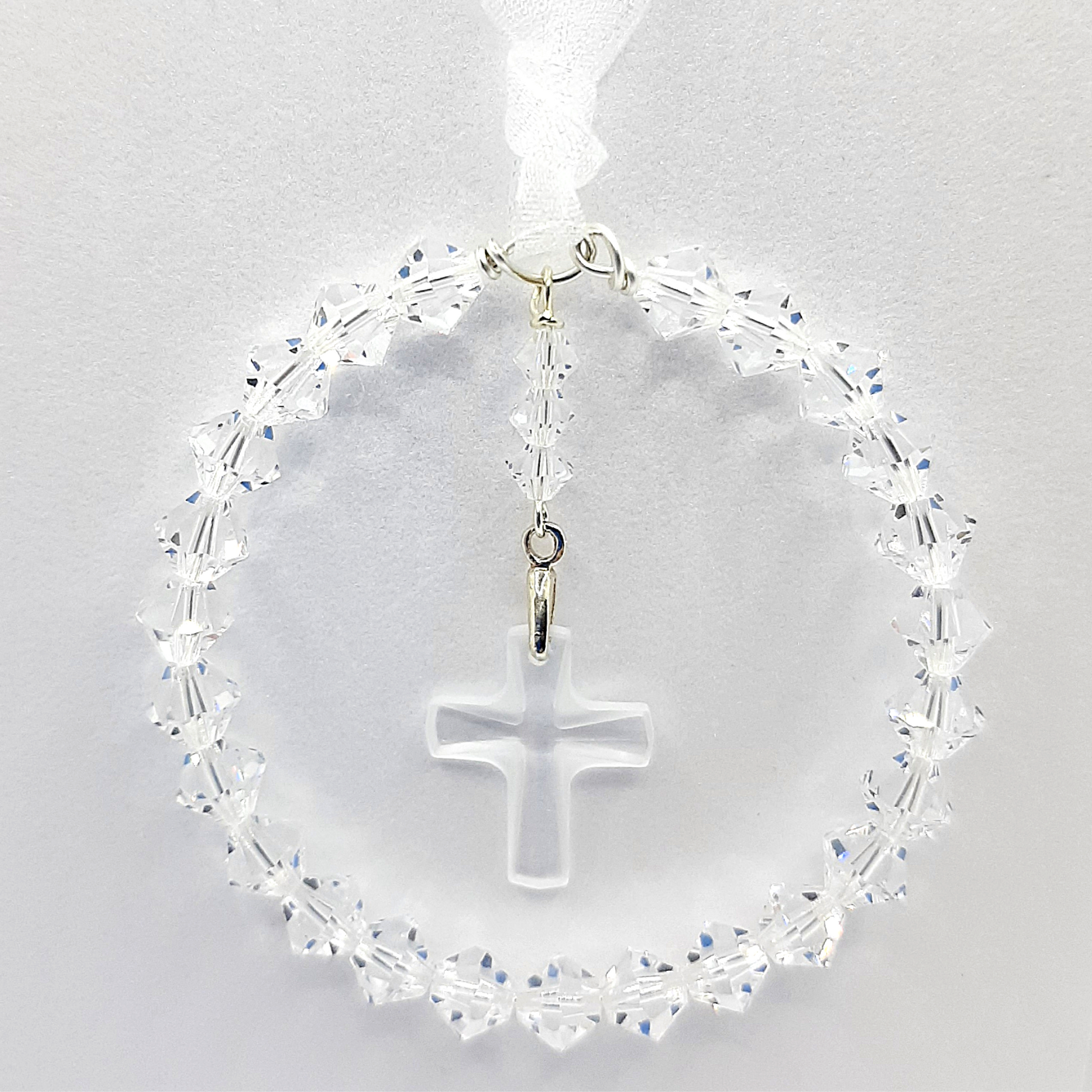 A circle of high grade austrian crystals surrounds a crystal cross suspended from the centre of the circle. Sparkling crystal ribbon completes the charm ready to hang on a gift card of your choice.