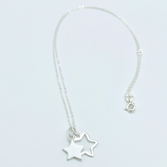 Two sterling silver stars, one solid, one outline hung from a sterling silver pendant. Part of the Message in a Bottle range
