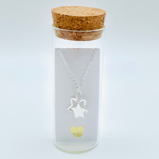 Two sterling silver stars, one solid, one outline hung from a sterling silver pendant and placed in a glass bottle. Part of the Message in a Bottle range. Behind the pendant is a scroll for you to add your own message.