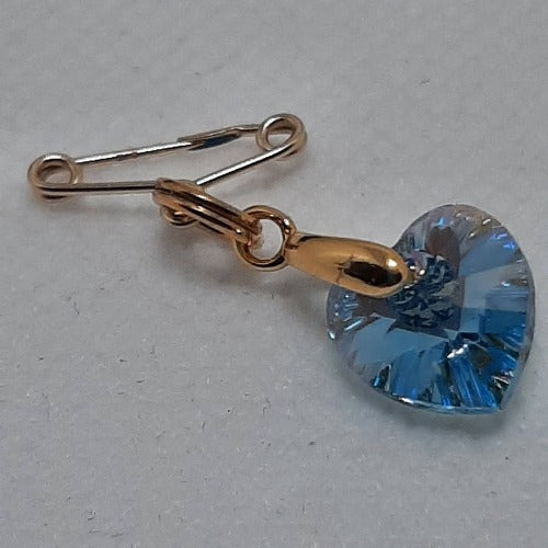 A secret something blue pin. A 9 carat gold pin holds a gold plated bail and a high quality austrian crystal blue heart.