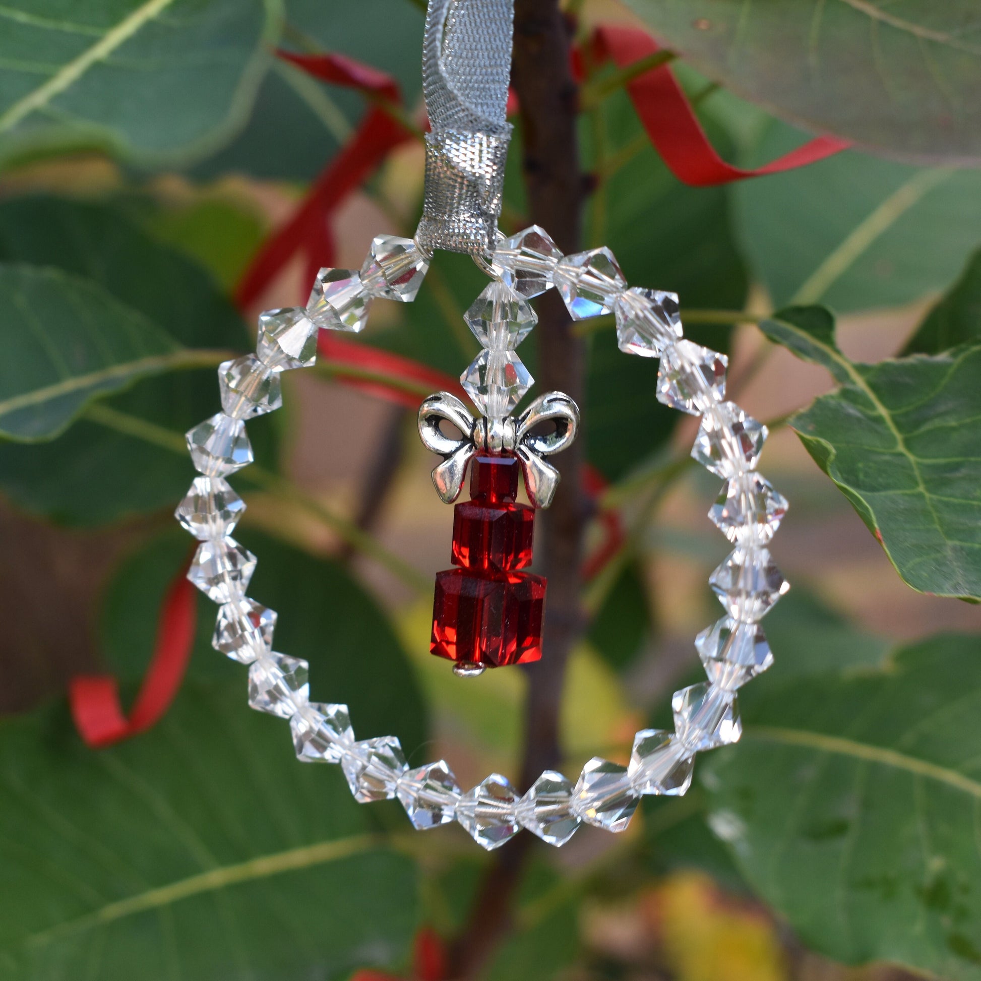 High quality clear crystals form a ring around a stack of cube crystals topped with a silver bow and finished with ribbon. Christmas tree ornament.
