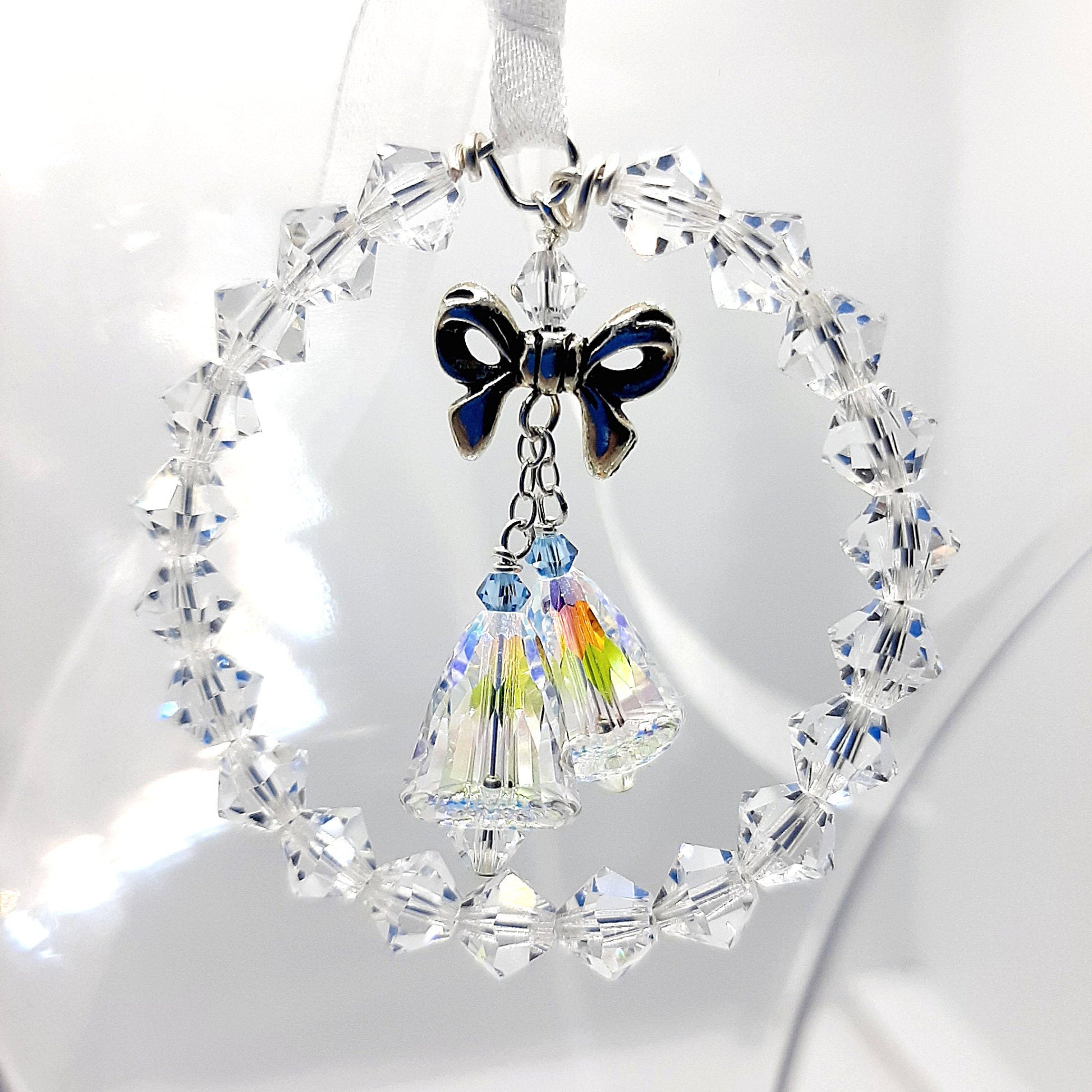 Crystal circle encasing two crystal wedding bells topped with a silver bow. Each bell has a tiny blue bead for Something Blue.